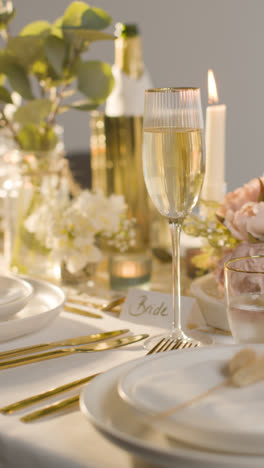 Vertical-Video-Of-Table-Set-For-Meal-At-Wedding-Reception-With-Champagne-And-Place-Card-For-Bride